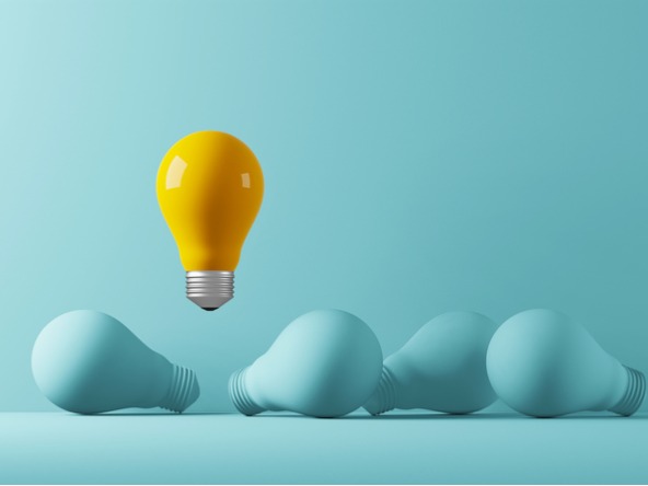 yellow lightbulb floats above blue ones against a blue background